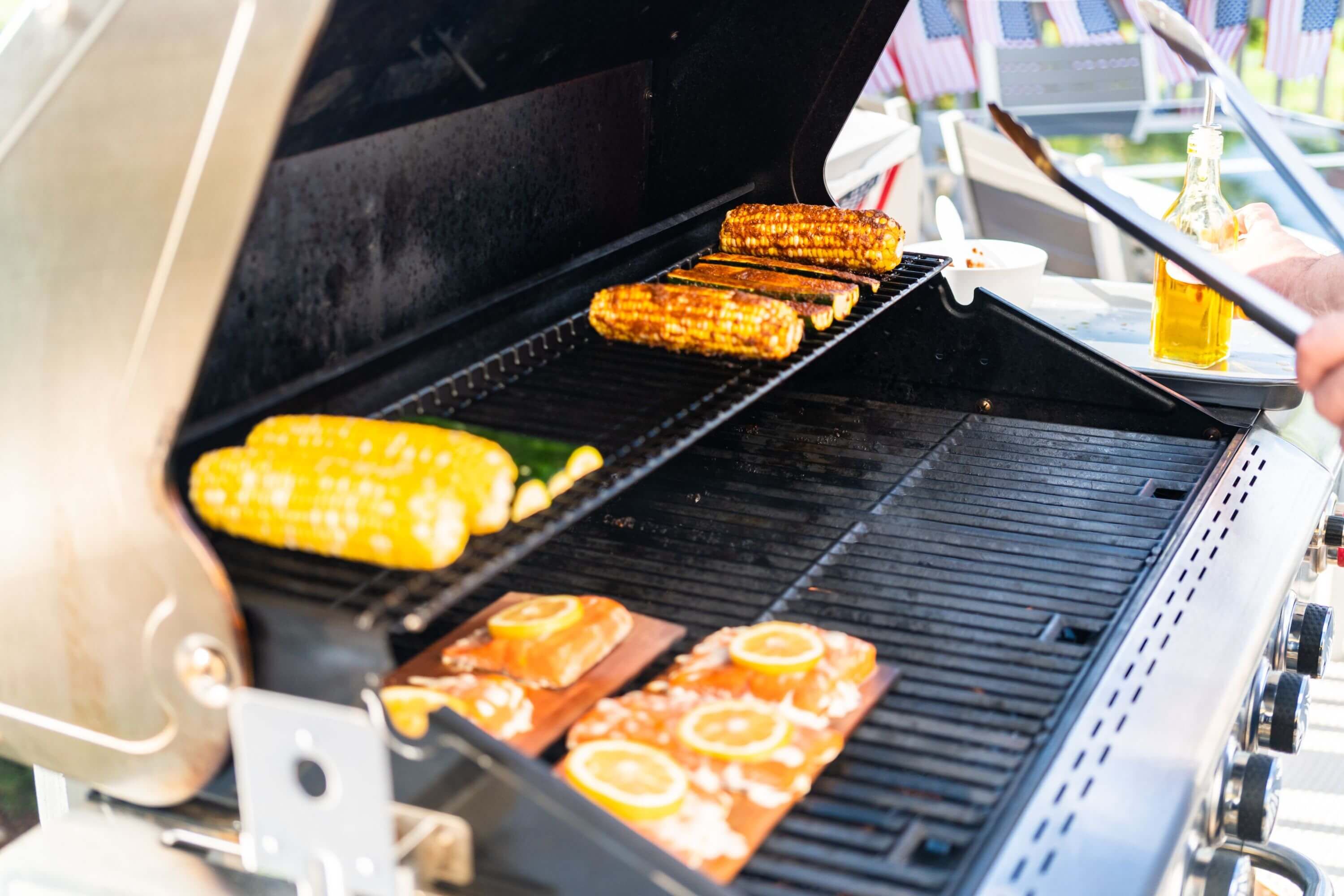 Indirektes Grillen von Maiskolben und Lachs auf der Holzplanke