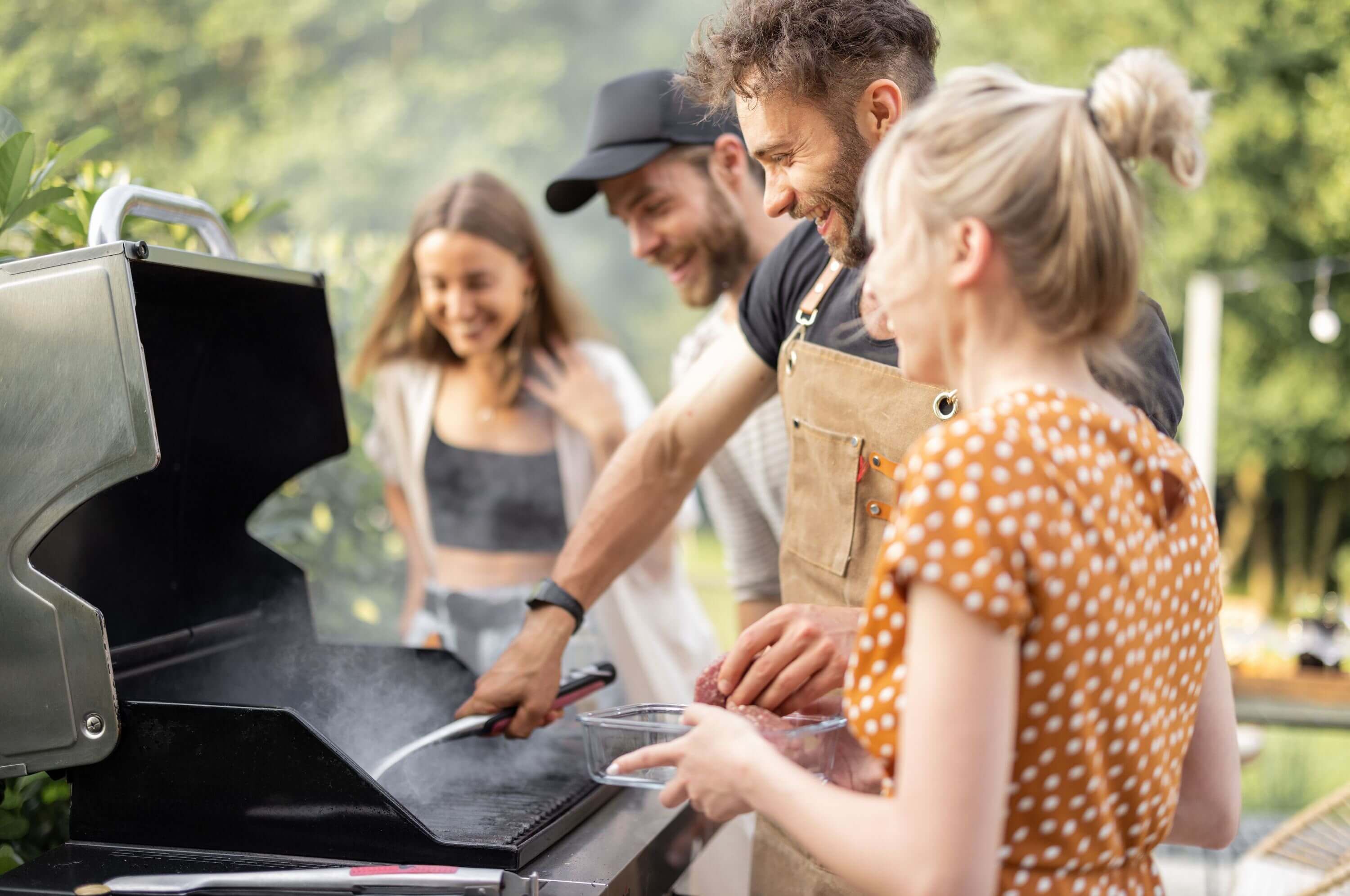 Freunde beim scharfen Angrillen von Fleisch auf dem Grill.