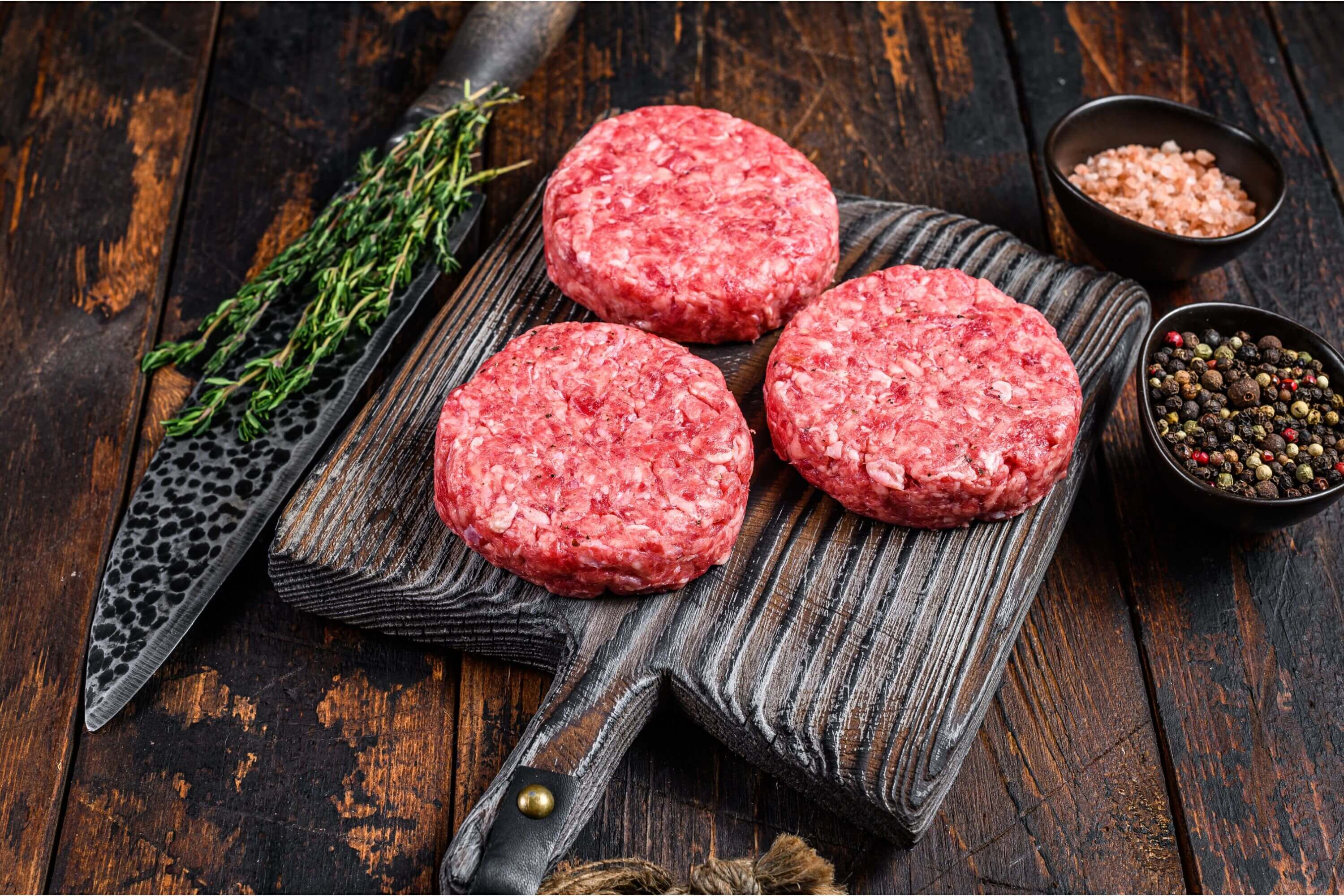 Burger-Patties auf einer Holzplanke