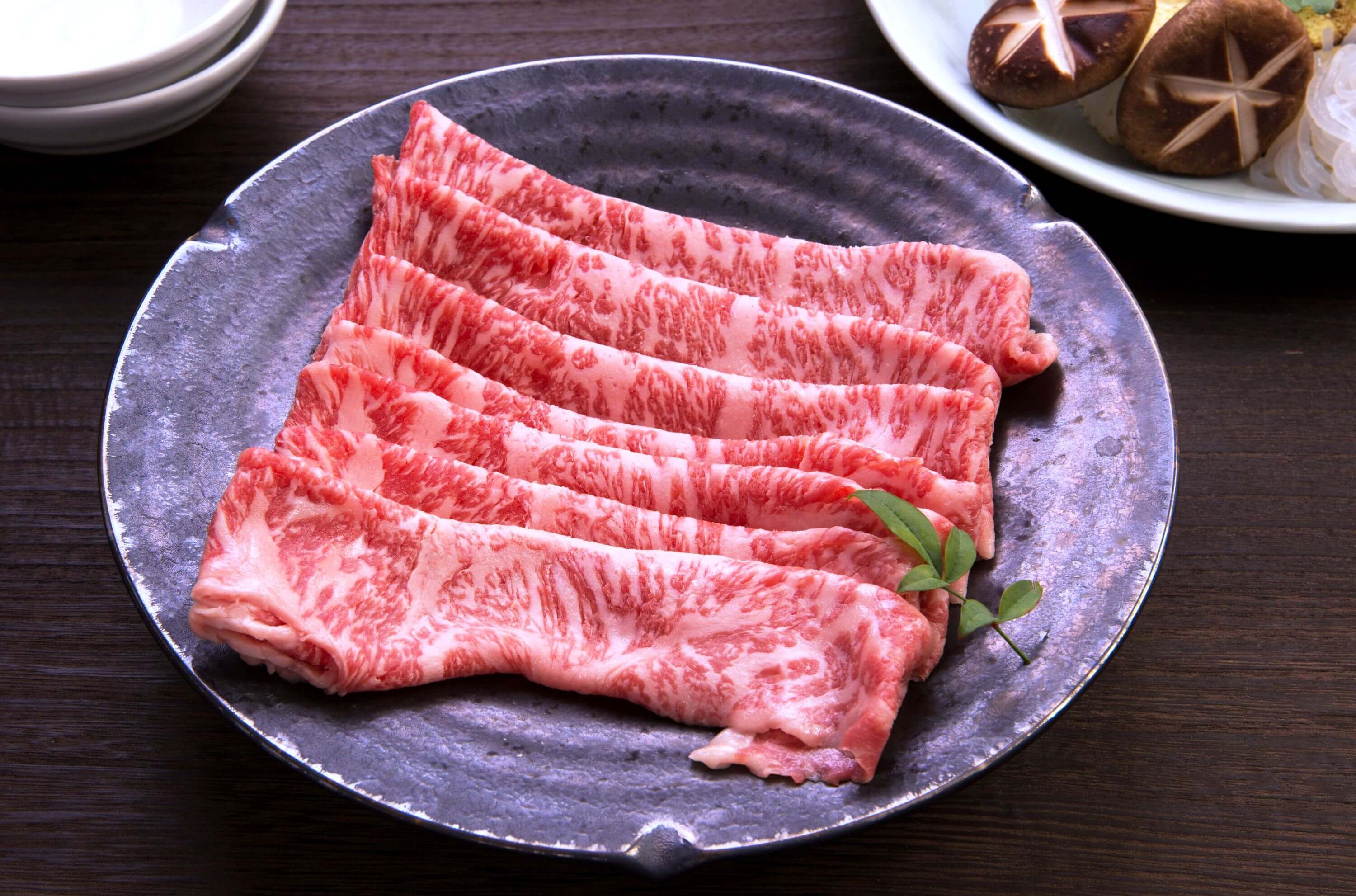 Dünn geschnittenes, marmoriertes Wagyu-Rindfleisch auf einem Teller, bereit für das japanische Barbecue Yakiniku..