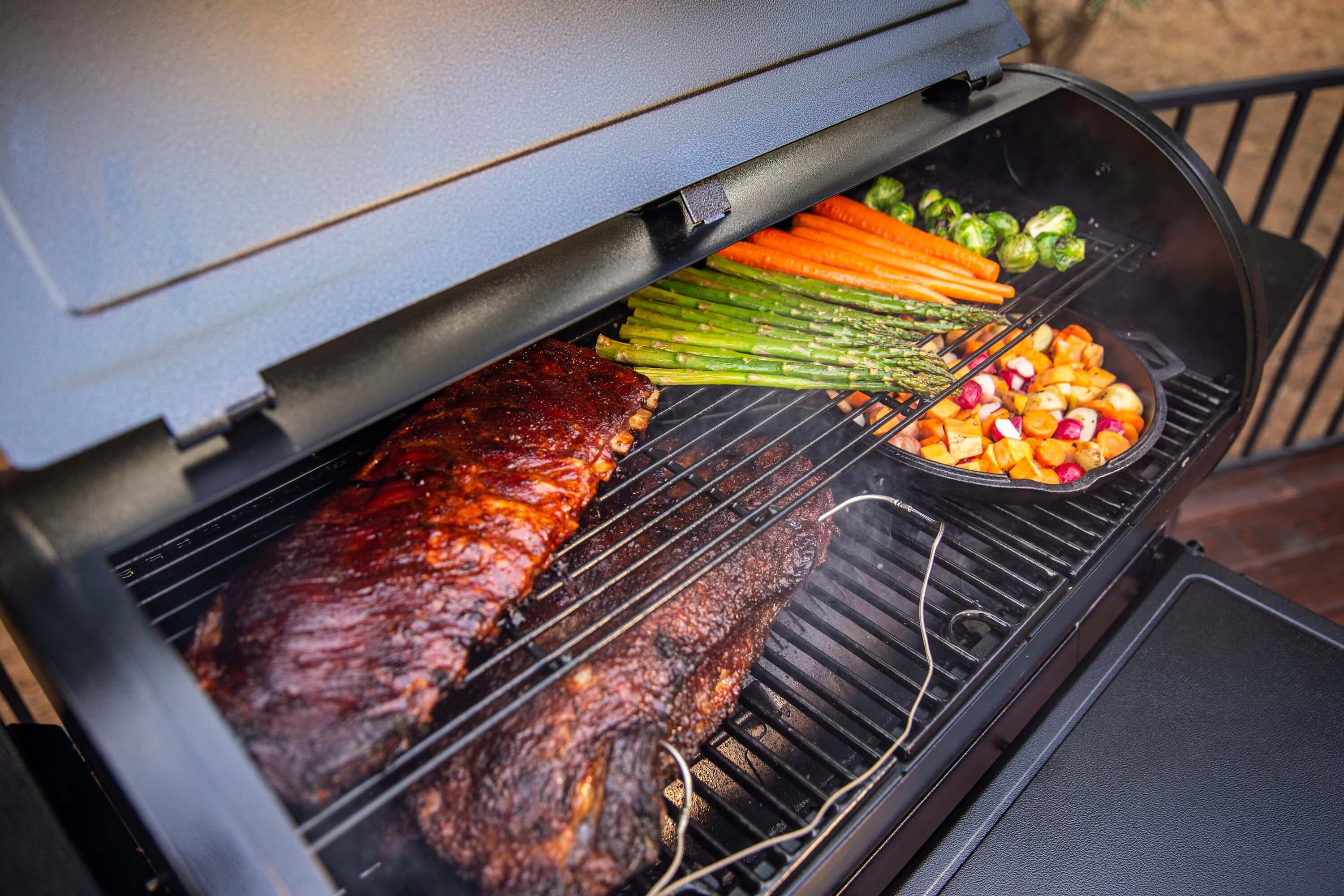 grillkammer-mit-spareribs-brisket-karotten-spargel-rosenkohl-und-grillgemüse-im-gusseisenpfännchen-auf-pelletgrill-mit-thermofühlern