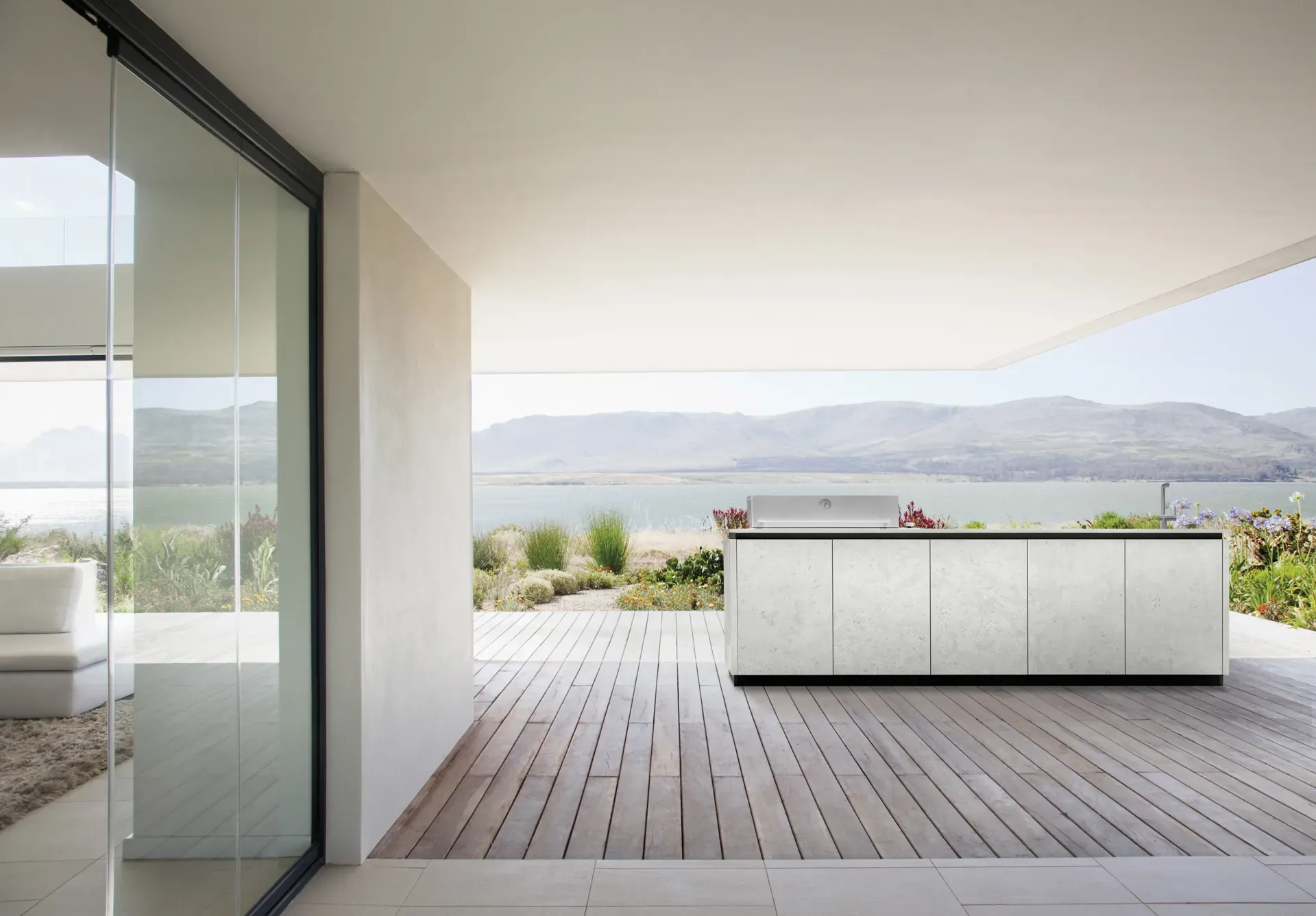 BURN SOL Outdoorküche mit heller Dekton-Arbeitsplatte auf einer Terrasse mit Meerblick