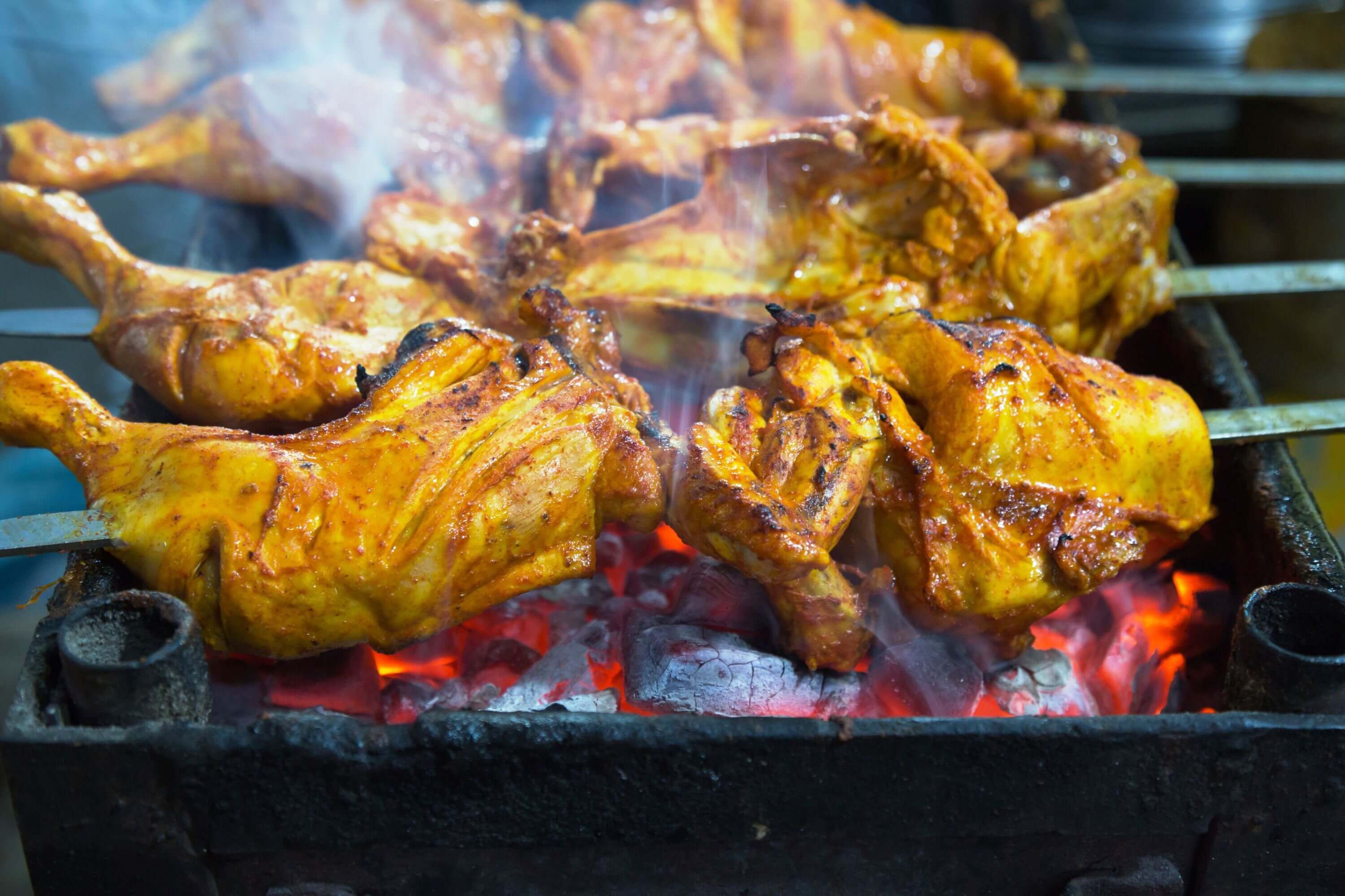 Geflügel wird direkt über der Glut gegrillt