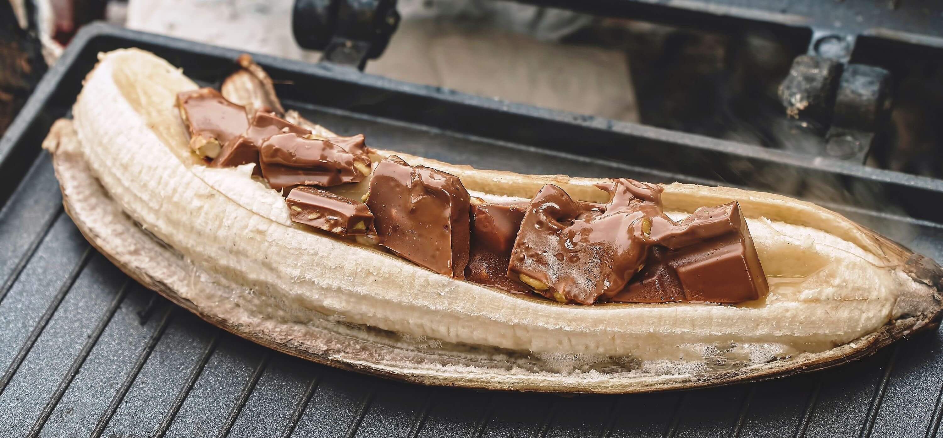 Gegrillte Banane mit geschmolzener Schokolade, eine leckere Dessertidee vom Grill, auf einem Grillrost zubereitet.