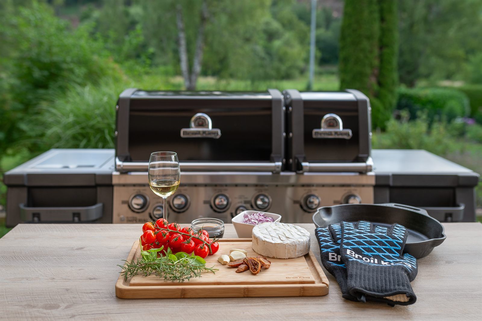 Grillplatz mit Broil King Gasgrill, Gusspfanne und den Zutaten fuer gegrillten Camembert