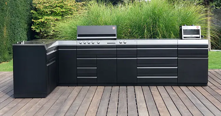 Otto Wilde Outdoorkueche auf einer großen Terasse vor grünem Garten