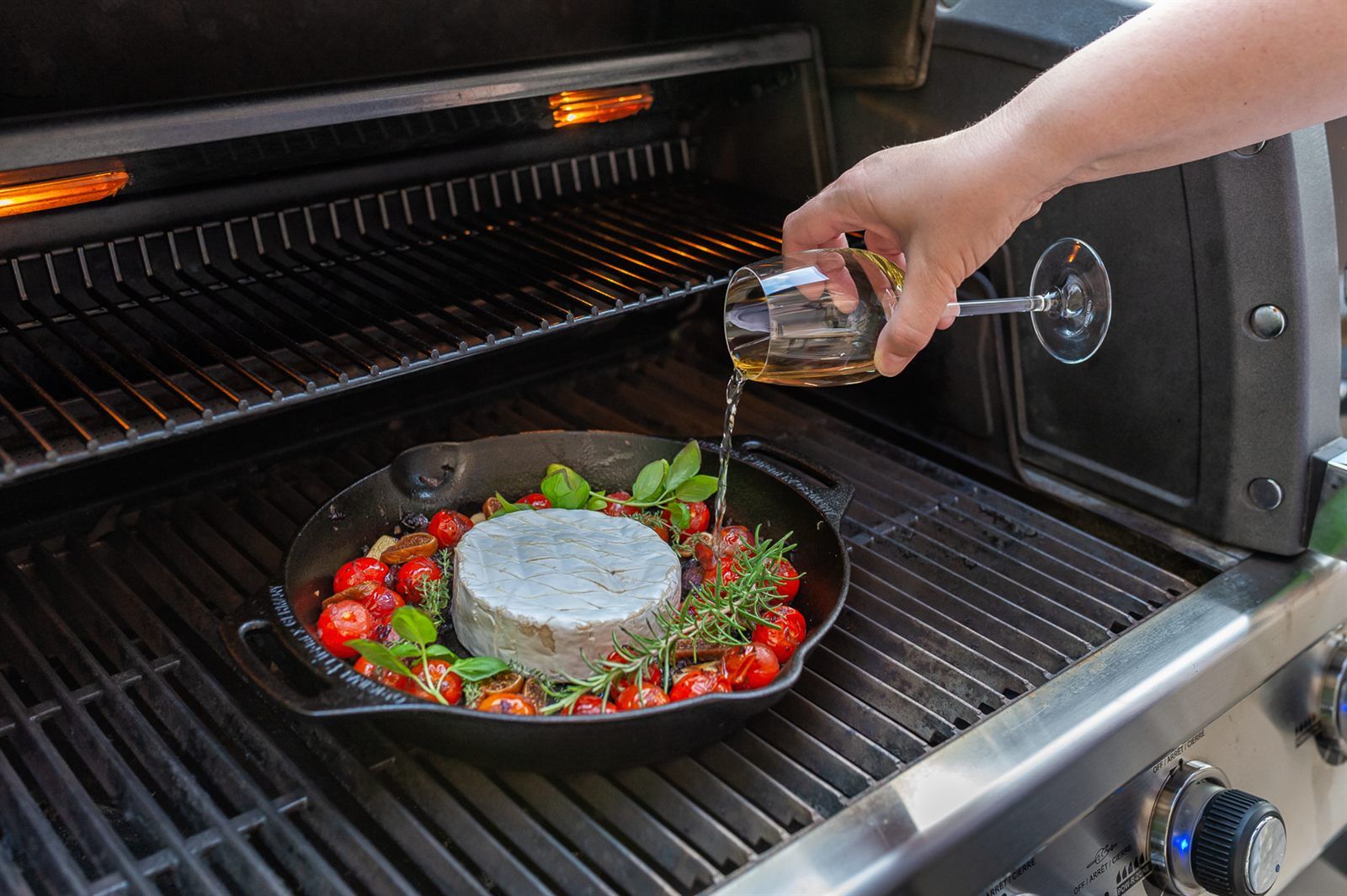 Weisswein wird zum Camembert in die gusseiserne Pfanne auf dem Grill gegossen
