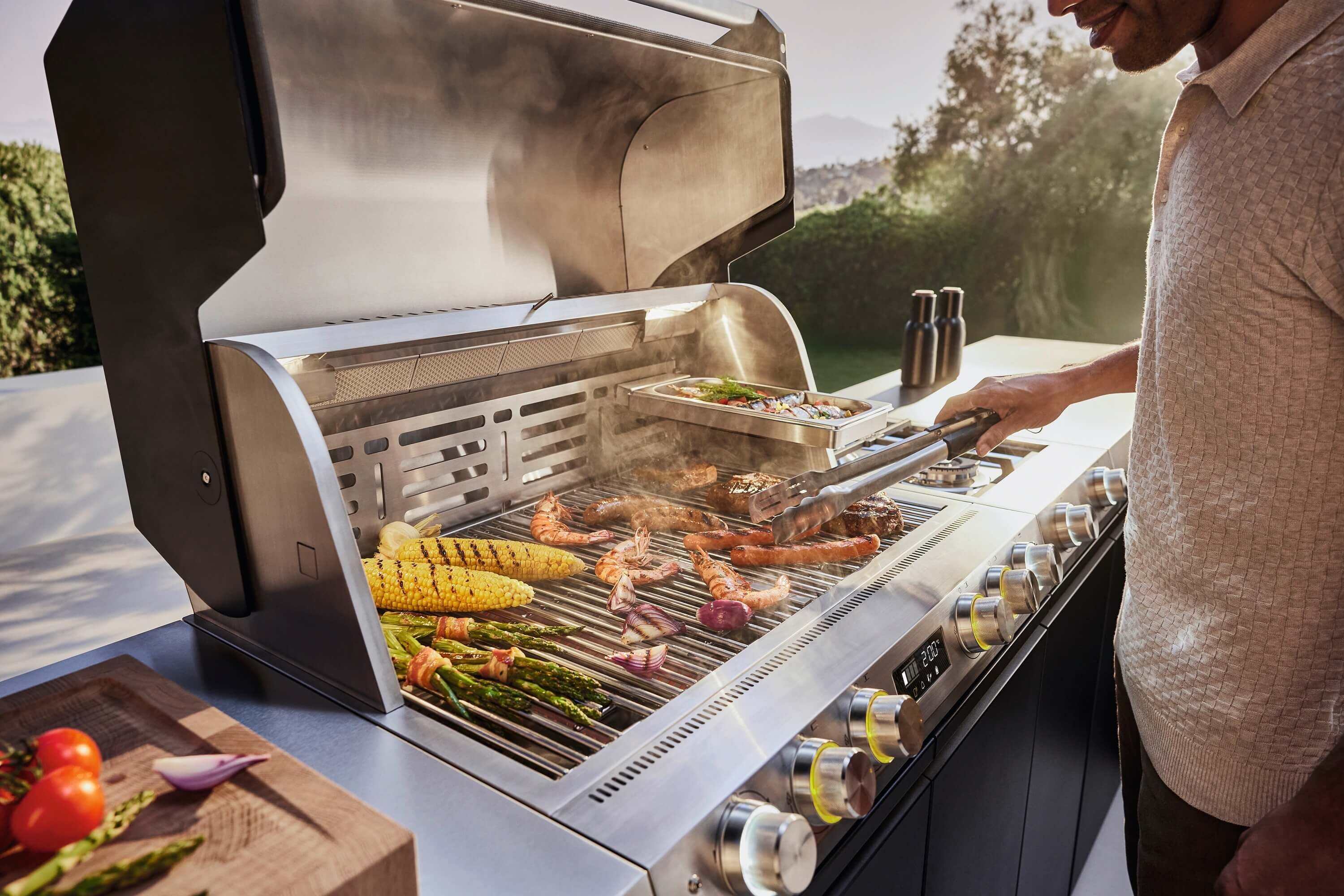 Miele Dreams – die smarte Outdoorküche mit Premium-Design und modularen Lösungen miele-dreams-fire-pro-iq-man-am-grillen-gemse-und-grillgut