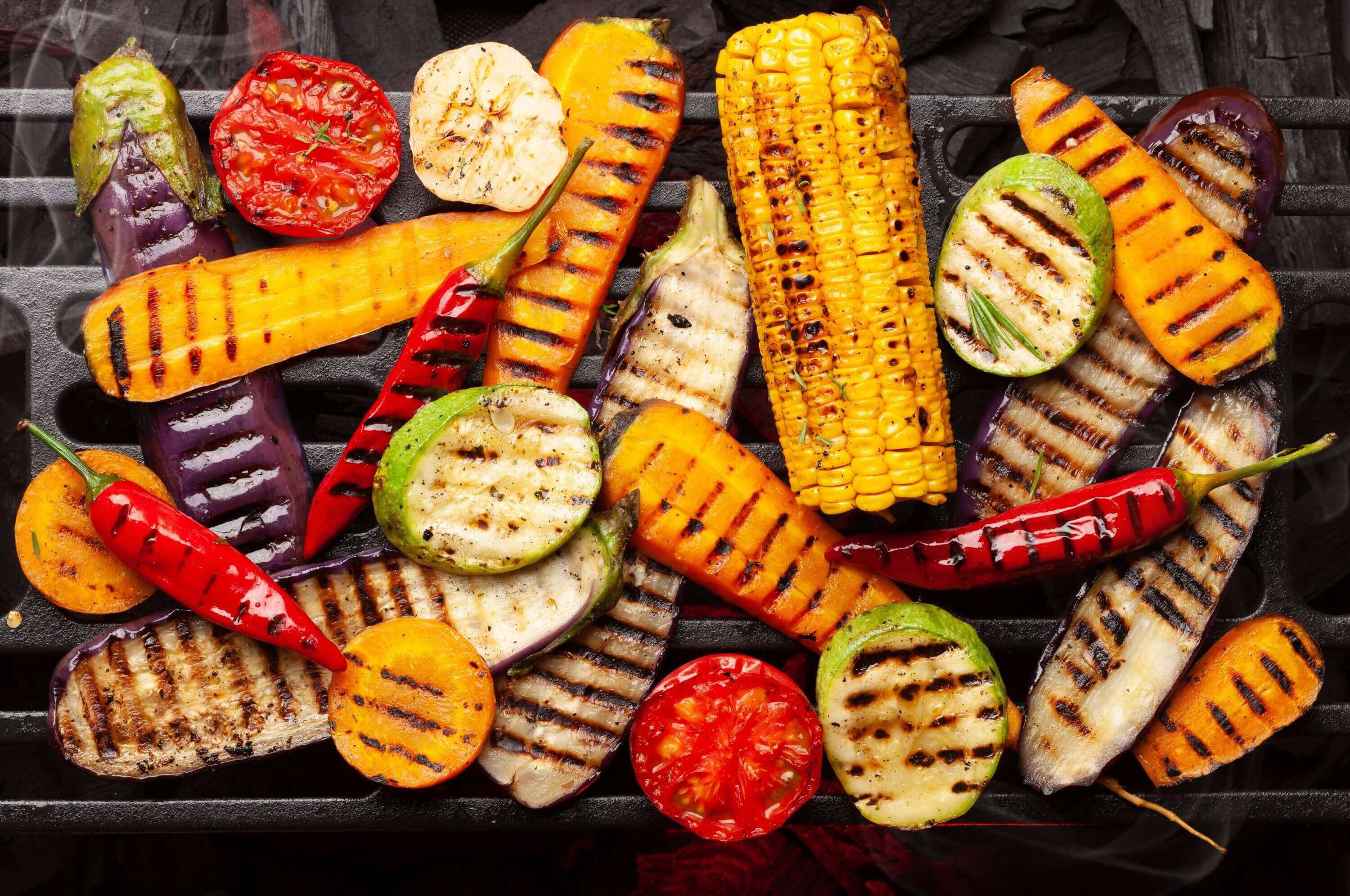 Buntes Grillgemüse wie Maiskolben, Zucchini, Aubergine und Paprika auf dem Grillrost, perfekt für gesundes Grillen.