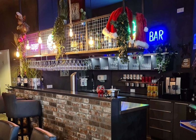 Bar im Grillcenter Nord mit Neon-Schriftzug, Gläserregal und Tresen aus Klinker