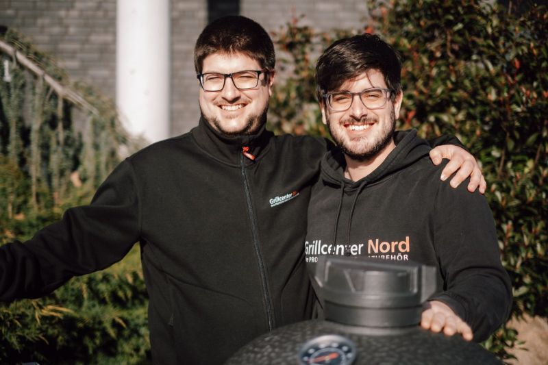 Nico und Sebastian vom Grillcenter Nord im Firmen-Hoodie an einem Keramikgrill